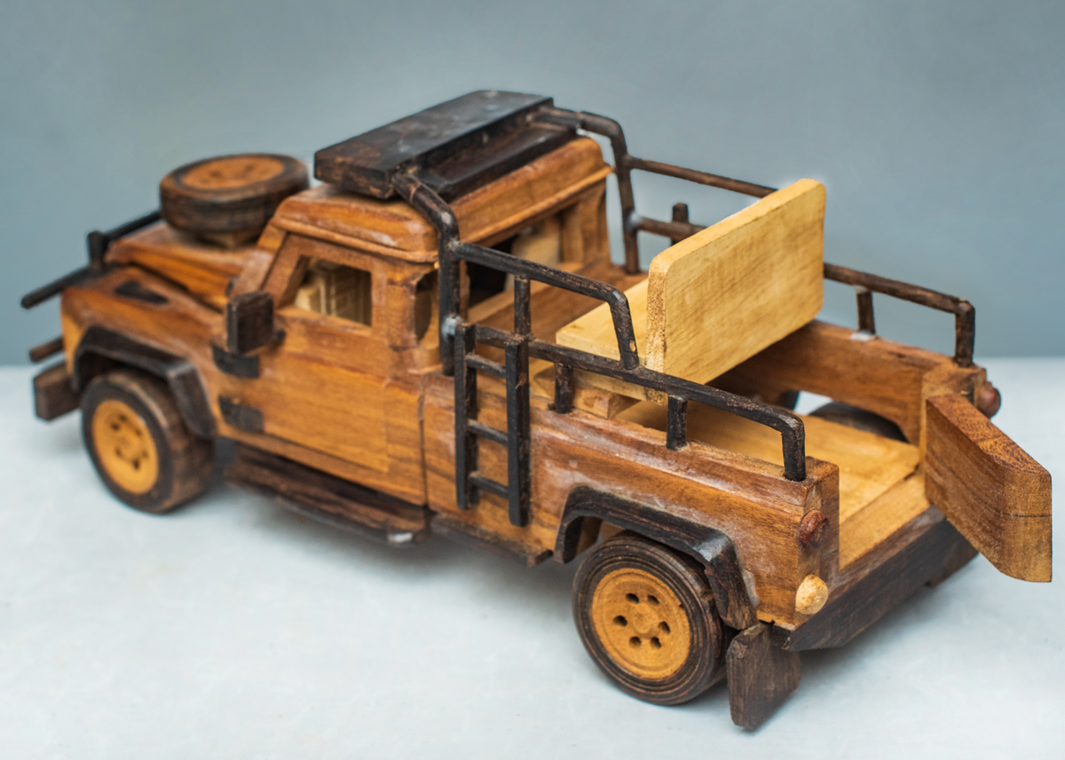 Handcrafted wooden safari game viewer from a rear angle, showing open seating, black safety rails, wooden wheels and a bonnet-mounted spare wheel.