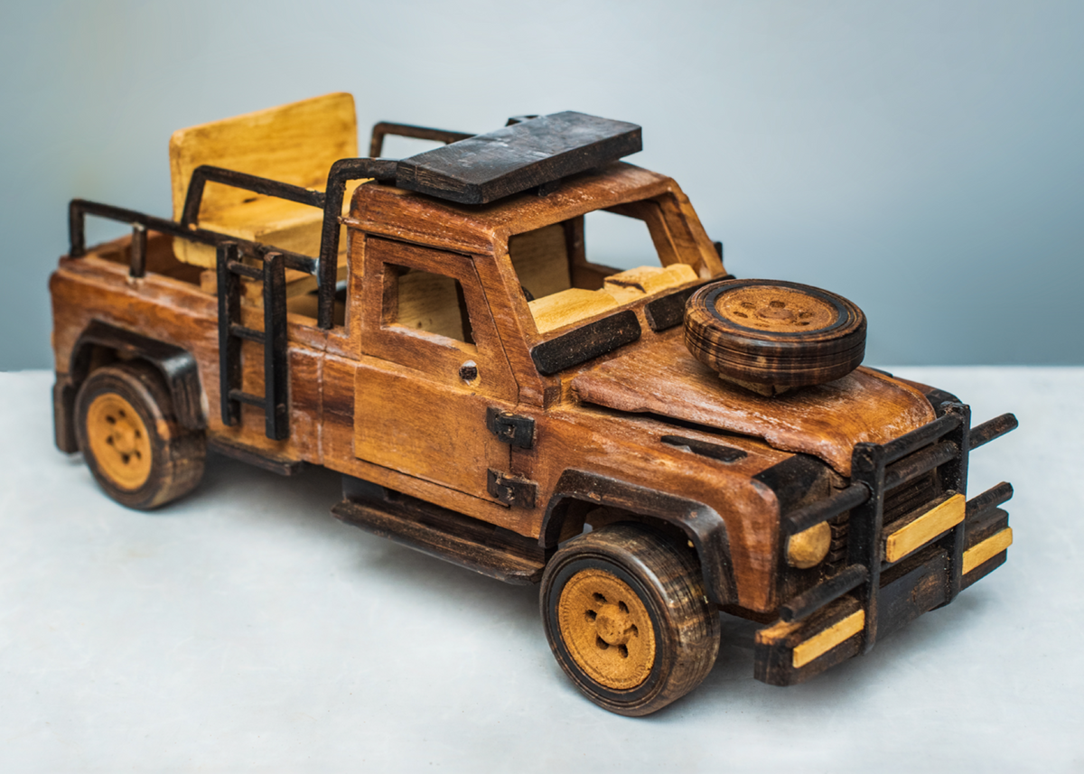 Handcrafted wooden safari game viewer from a front angle, showing its bonnet-mounted spare wheel, open rear seating, black safety rails and wooden wheels.