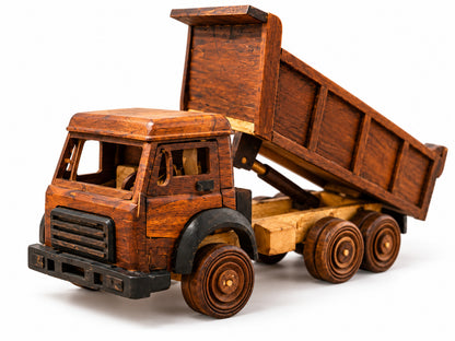 Handmade wooden dump truck viewed from the front, showing its grille, six wheels and raised tipping bed against a white background.
